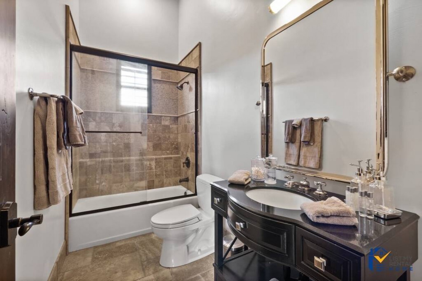 Step into your private spa-like bathroom with elegant stone tile shower, plush towels, and thoughtful amenities perfectly arranged for your comfort.