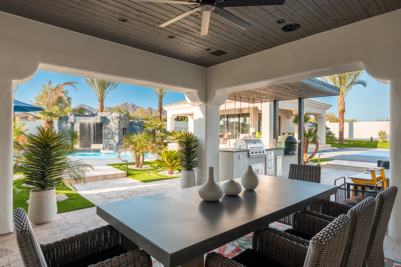 Dine outdoors under the ceiling fan at this covered patio, overlooking the sparkling pool, lush tropical landscaping, and mountain views. Your perfect setting for alfresco meals.