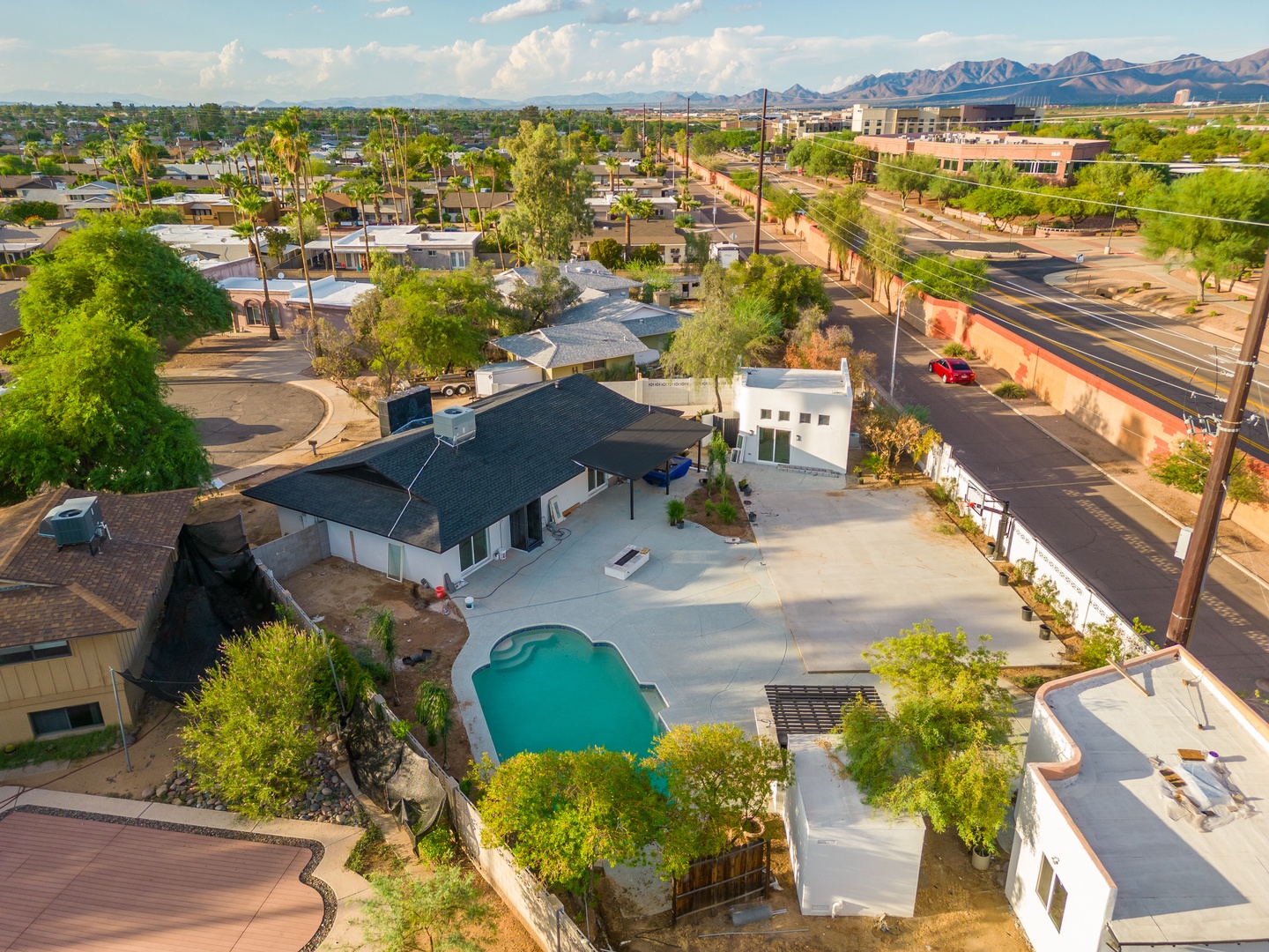 Aerial view of the property nestled in a scenic neighborhood with palm-lined streets and stunning mountain backdrop, showcasing the private pool and spacious outdoor areas.