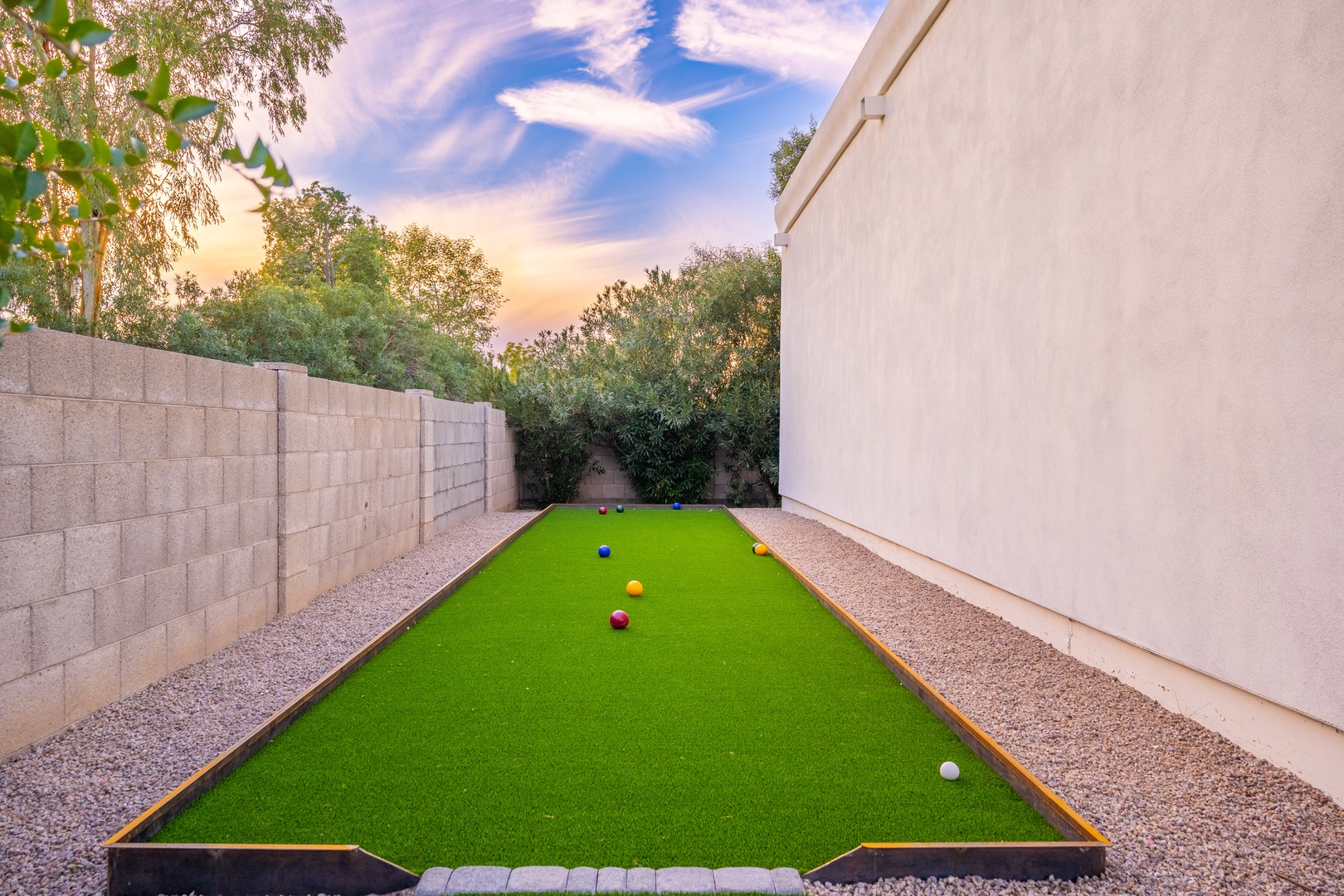 An outdoor putting green nestled in a private courtyard, framed by lush trees and sunset skies—perfect for leisurely games during your stay.