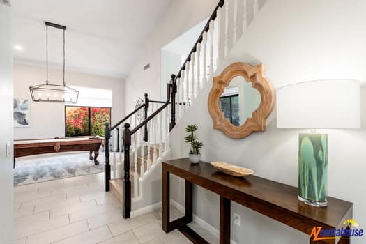Your stylish entryway welcomes you with warm wood accents, a statement mirror, and an elegant staircase leading to your private retreat upstairs.