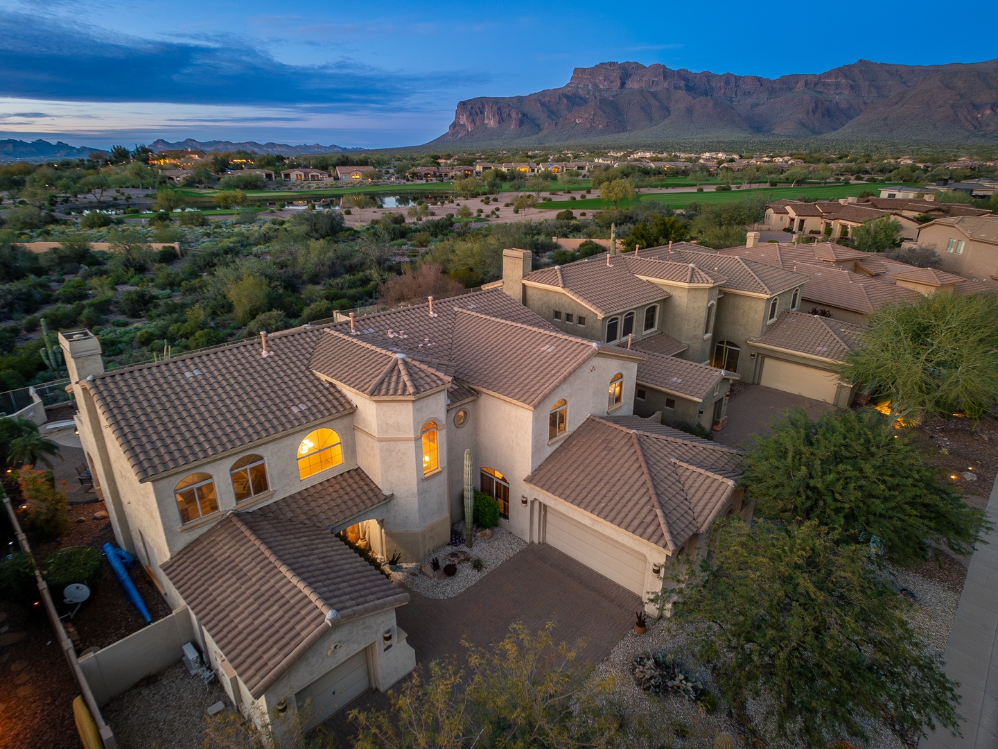 Stunning property nestled beneath dramatic mountain ridges in a serene desert community, offering expansive views and a peaceful neighborhood setting at twilight.
