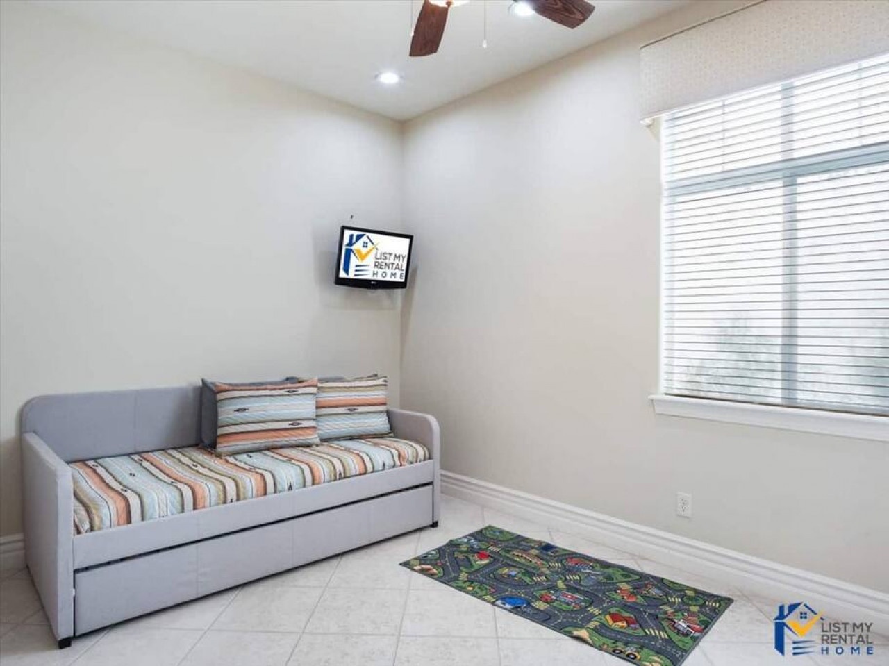 Unwind in your cozy sitting area with comfortable daybed, wall-mounted TV, and bright natural light streaming through the window.