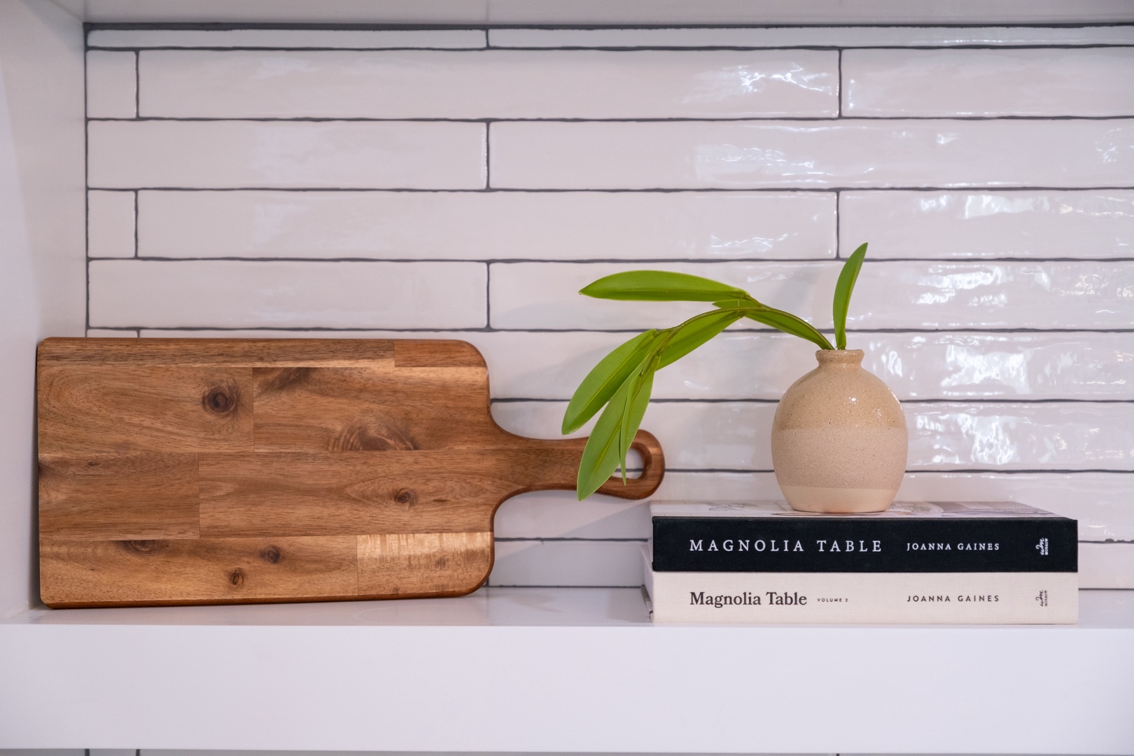 Crisp subway tile backsplash sets the stage for your culinary creations, with thoughtful touches like a rustic cutting board and fresh greenery adding warmth to your kitchen.