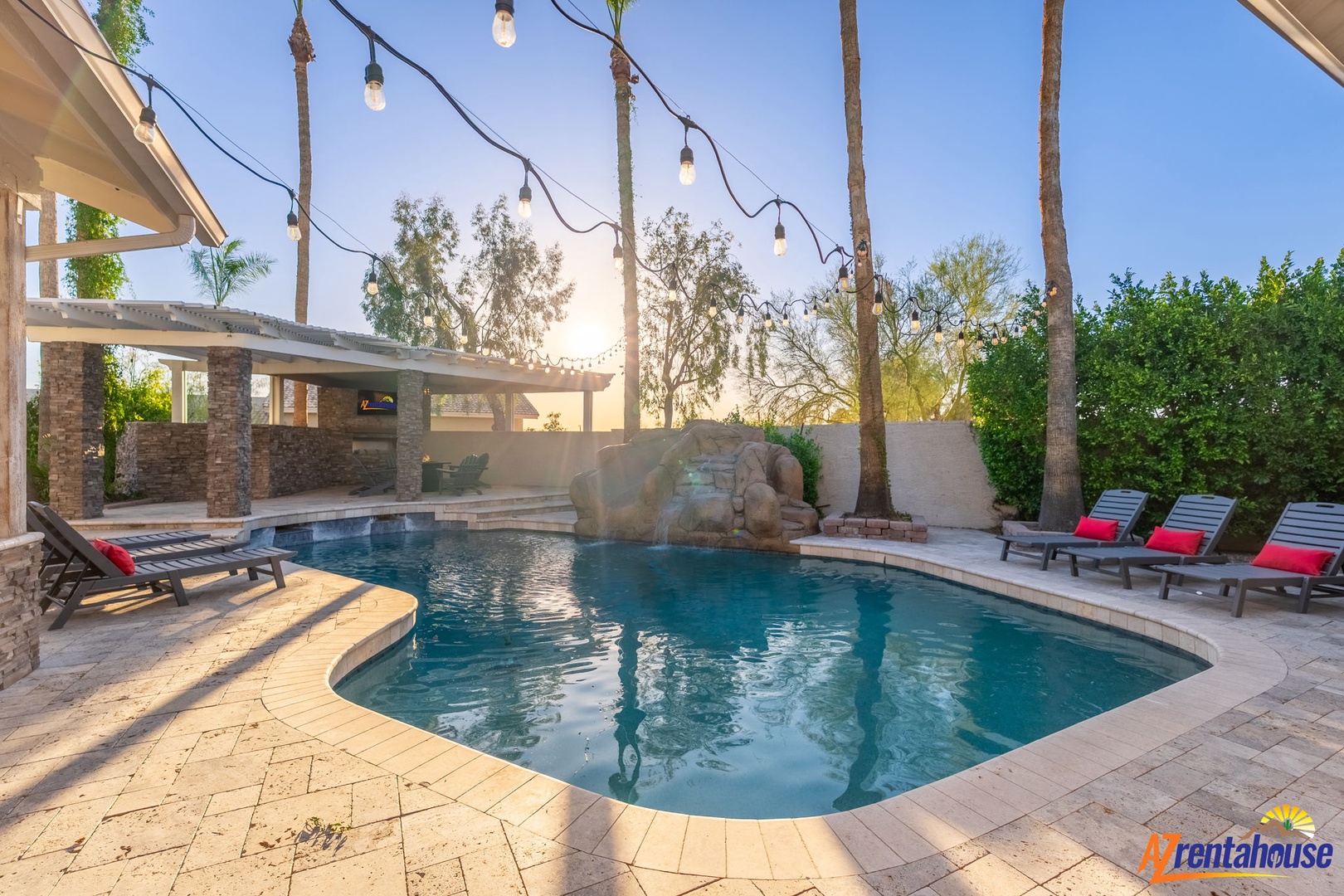 This private oasis features a sparkling pool beneath swaying palms, string lights overhead, and loungers inviting you to unwind in the golden desert sun.