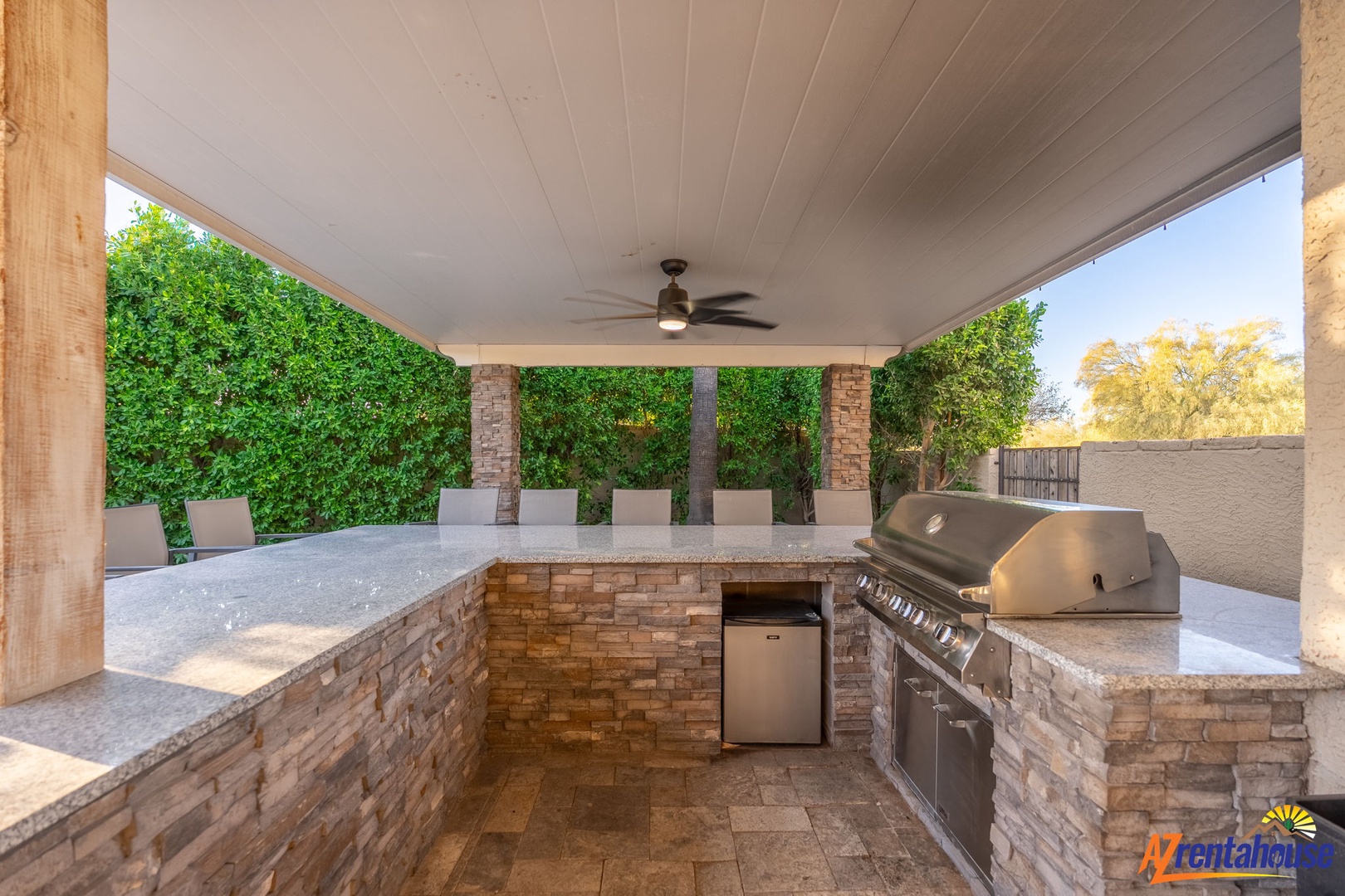 Your private outdoor kitchen awaits with a built-in grill and ample counter space, perfect for cooking under the covered patio surrounded by lush greenery.