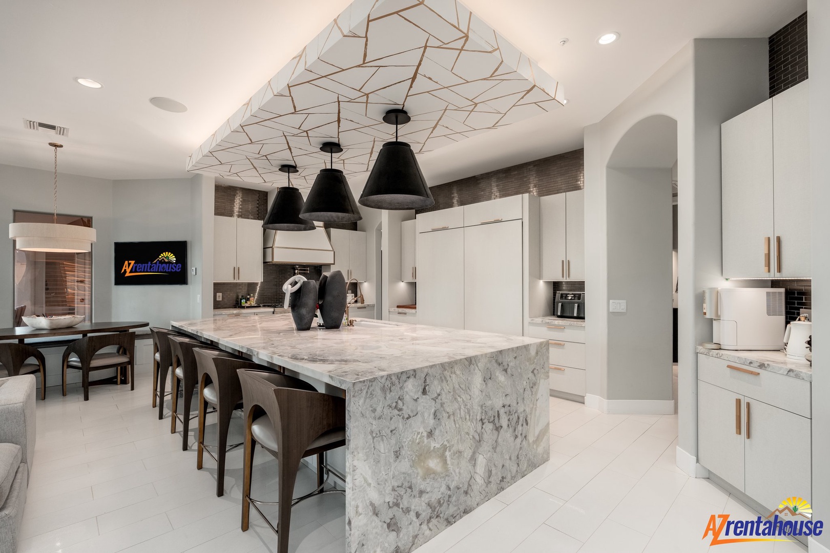 Your gourmet kitchen features marble island seating, modern appliances, and striking geometric ceiling details for memorable meal preparation.