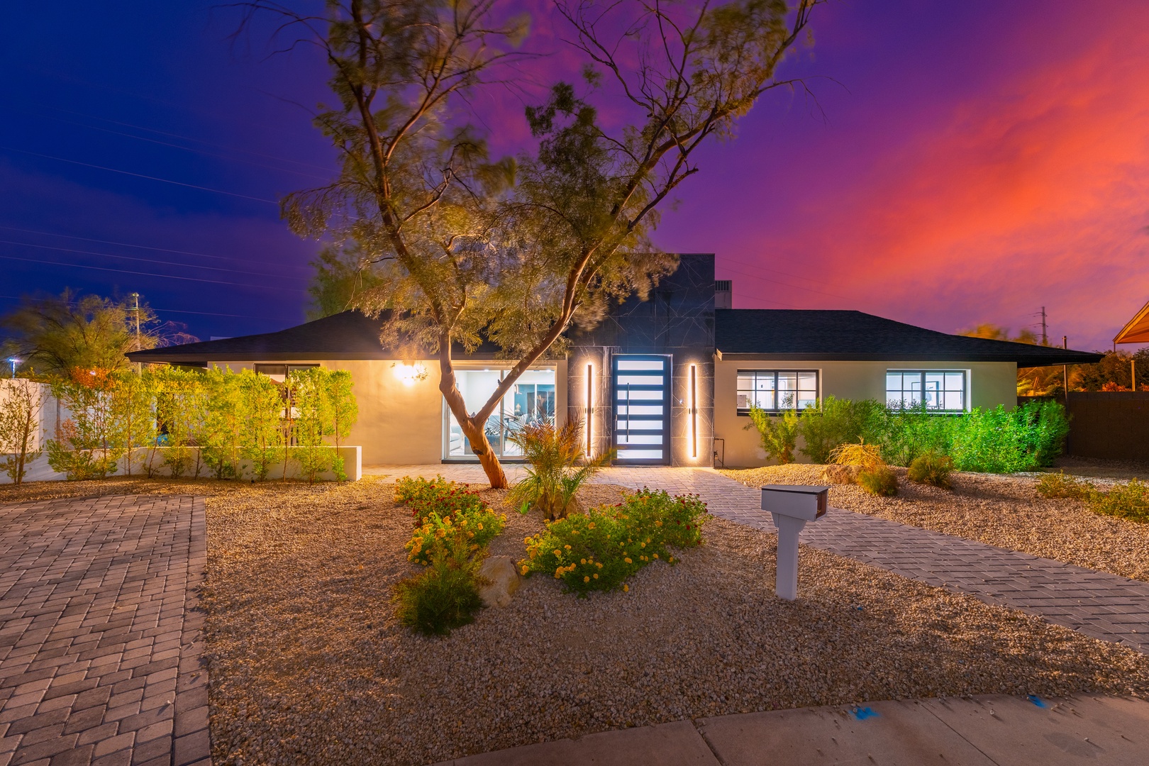 This stunning property features a modern exterior with desert landscaping and dramatic sunset skies creating a vibrant backdrop for the surrounding neighborhood.