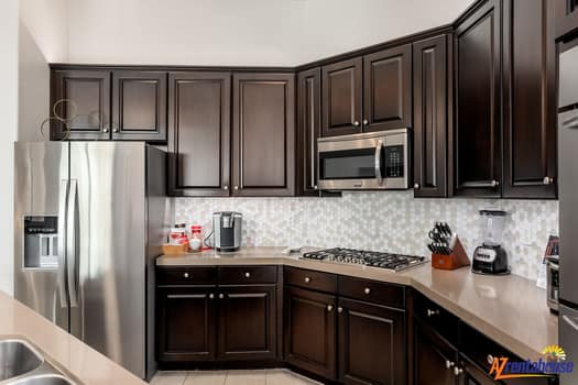 Prepare your favorite meals in this fully equipped kitchen featuring stainless steel appliances, granite countertops, and a stylish hexagonal tile backsplash.