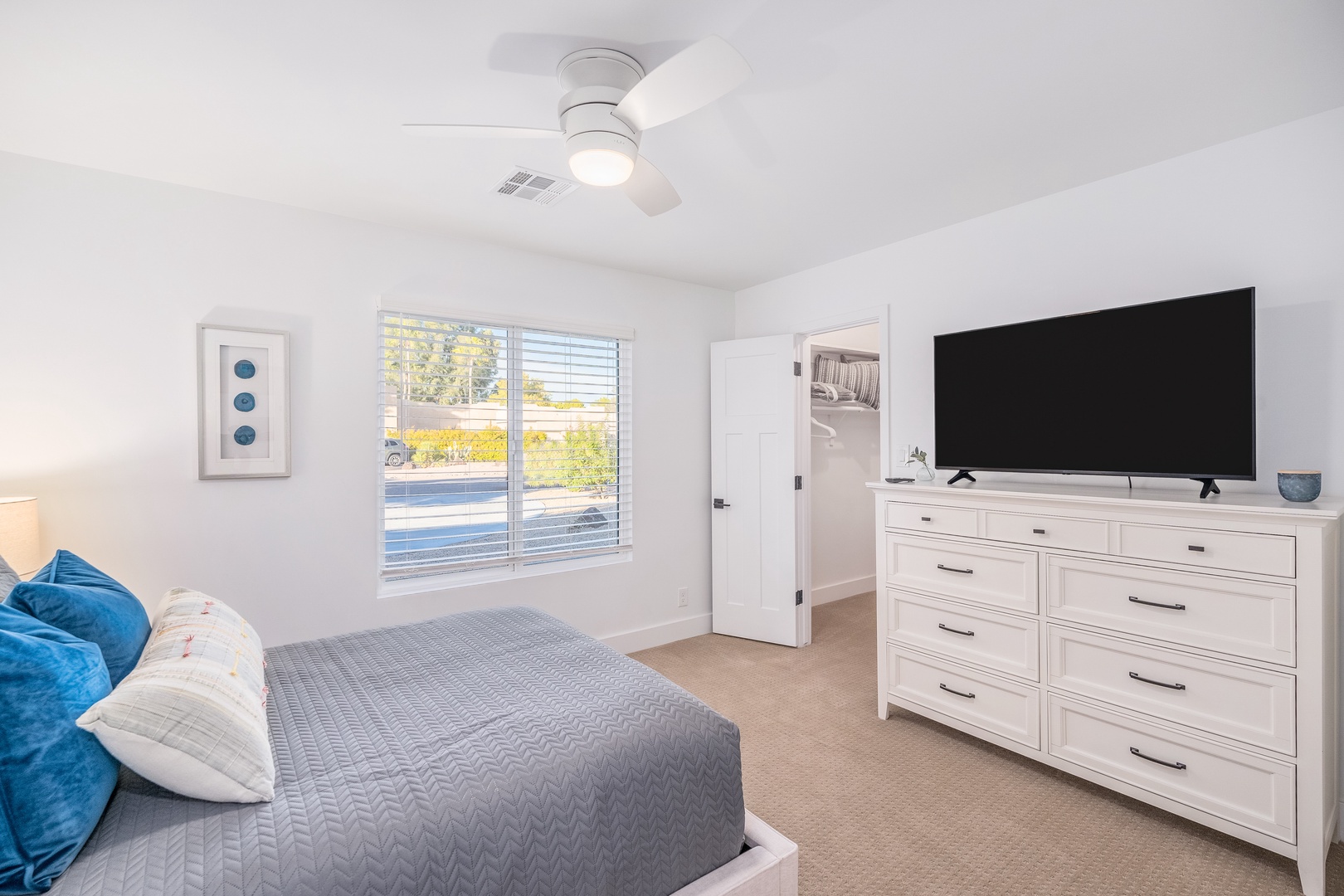 Your peaceful retreat features a plush bed dressed in soft linens, a large flat-screen for cozy nights in, and a ceiling fan to keep you comfortable—plus natural light and a walk-in closet for all your essentials.