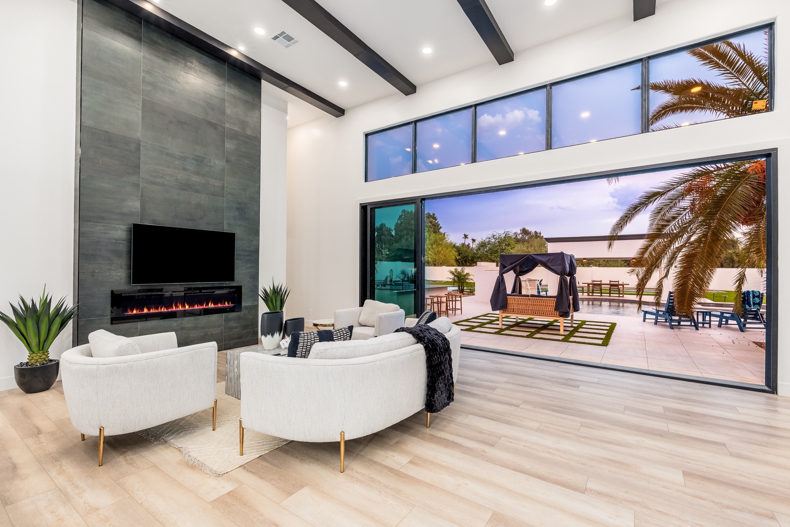 Unwind in your spacious living room where sleek modern design meets comfort, featuring a cozy fireplace, vaulted ceilings with exposed beams, and seamless indoor-outdoor flow to your private patio oasis.