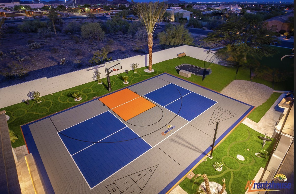 Aerial view showcasing a full-sized basketball court with professional markings, surrounded by manicured landscaping and desert scenery.