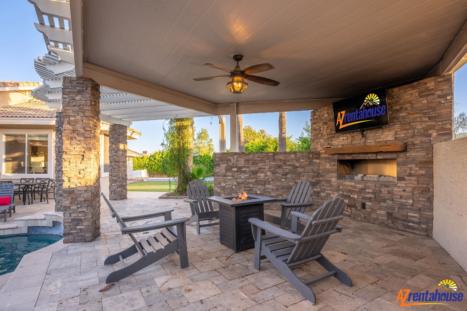 Unwind in your private covered patio with a cozy fire table, ceiling fan, and outdoor TV—perfect for relaxing evenings by the pool.