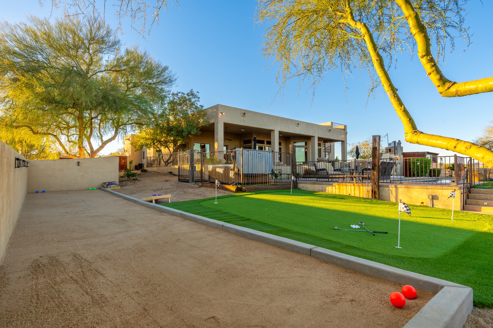 Modern desert property featuring a private putting green, covered patio, and spacious yard—perfect for outdoor relaxation and recreation under sunny Arizona skies.
