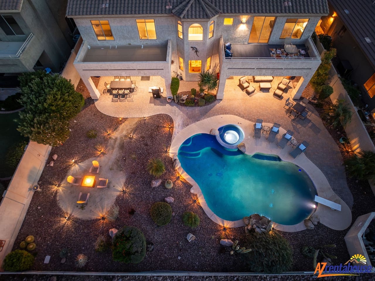 Stunning aerial view of this luxury vacation home featuring a custom-shaped pool, spa, and multiple outdoor entertaining areas surrounded by elegant landscaping.