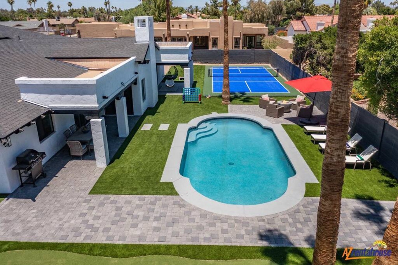 Modern desert oasis featuring swimming pool, tennis court, and spacious outdoor entertaining areas surrounded by palm trees.
