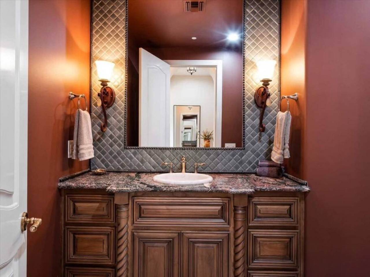 Step into this elegant bathroom with a stunning quilted mirror backsplash, granite counters, and warm bronze finishes that create a luxurious, spa-like retreat for your stay.