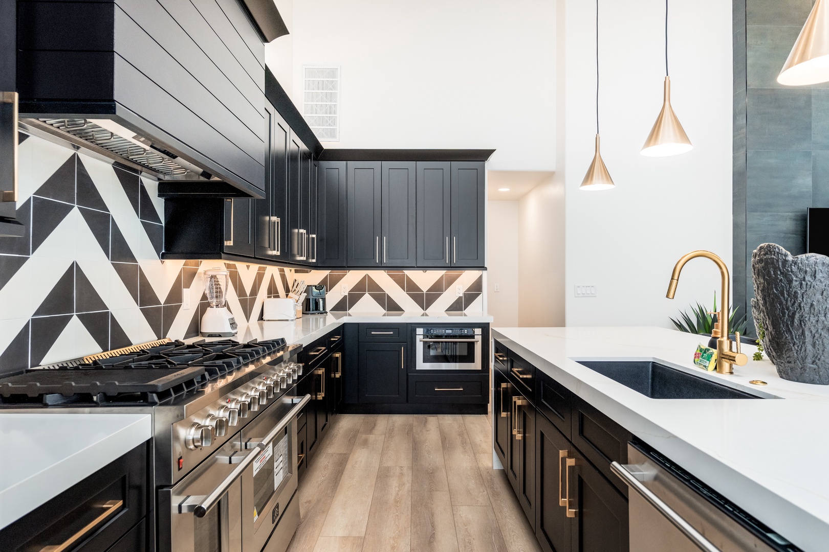 Sleek black cabinetry with gold accents and bold geometric tile—your gourmet kitchen invites culinary creativity with professional-grade appliances and bright, airy design.