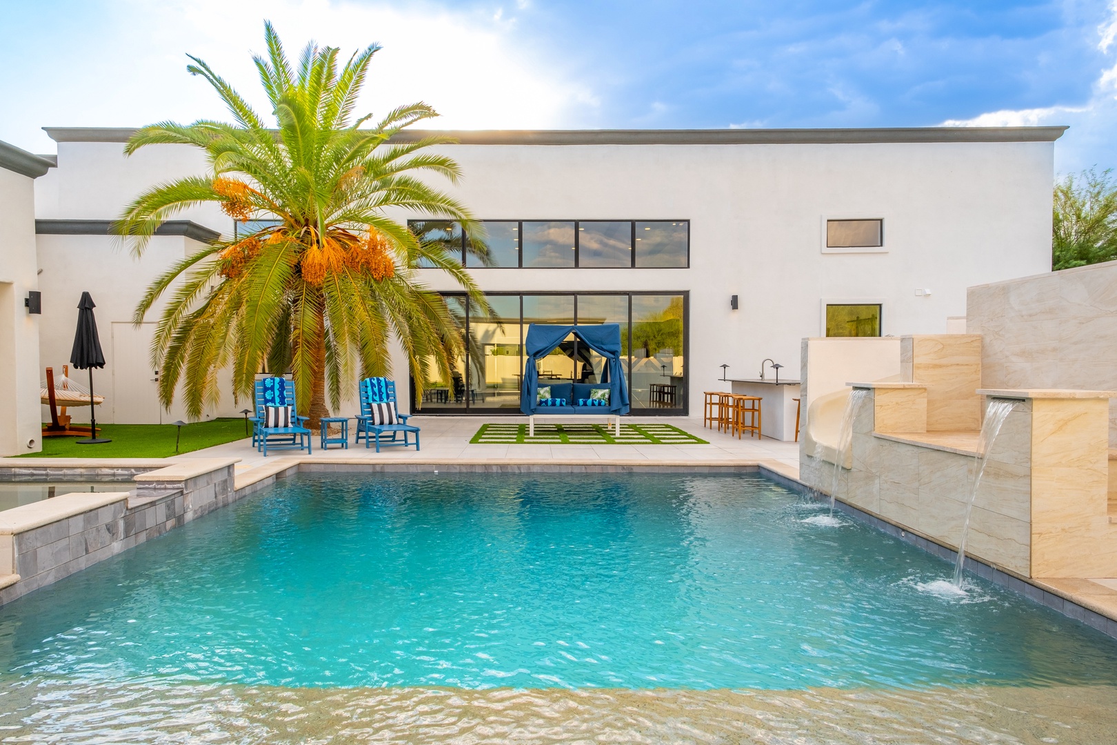 Dive into your private oasis, where a sparkling pool meets modern architecture and swaying palms—your perfect poolside retreat under sunny skies awaits.