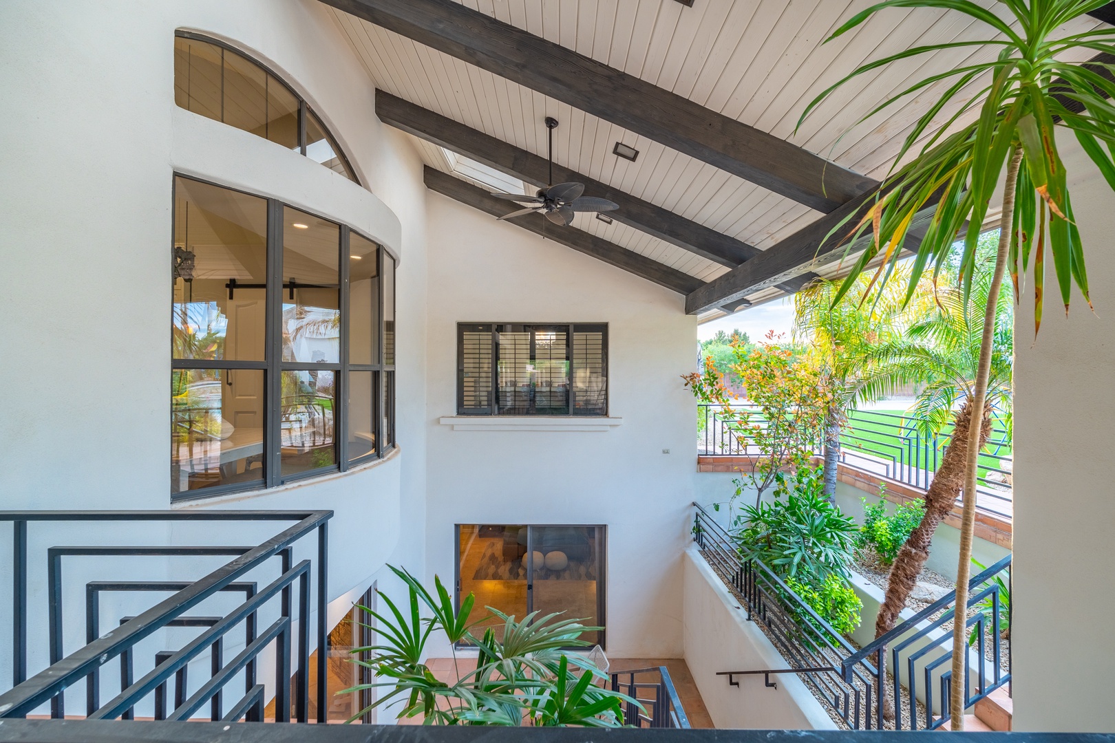 Step into your private retreat where vaulted ceilings, exposed beams, and lush tropical greenery create a serene sanctuary. Relax in this bright, airy space designed for ultimate comfort.