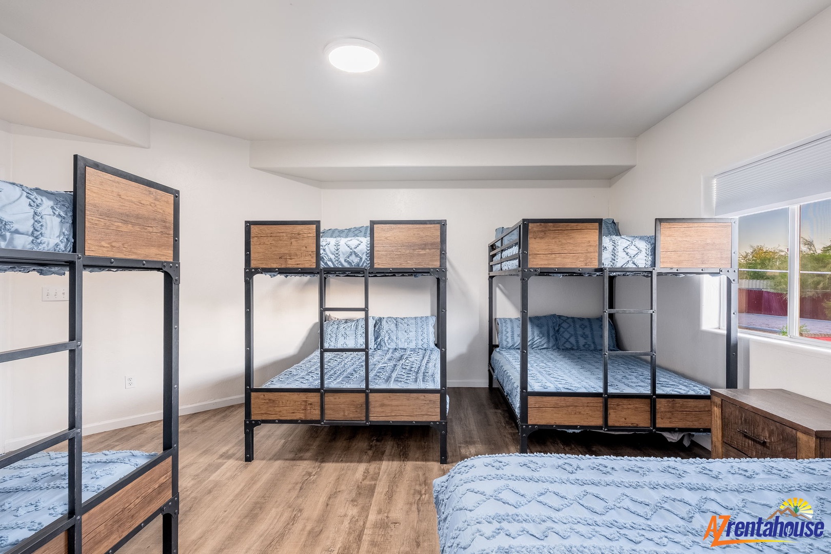 Gather your crew in this bright bunk room, where modern industrial beds with warm wood accents create a cozy group retreat, perfect for family adventures and making memories together.