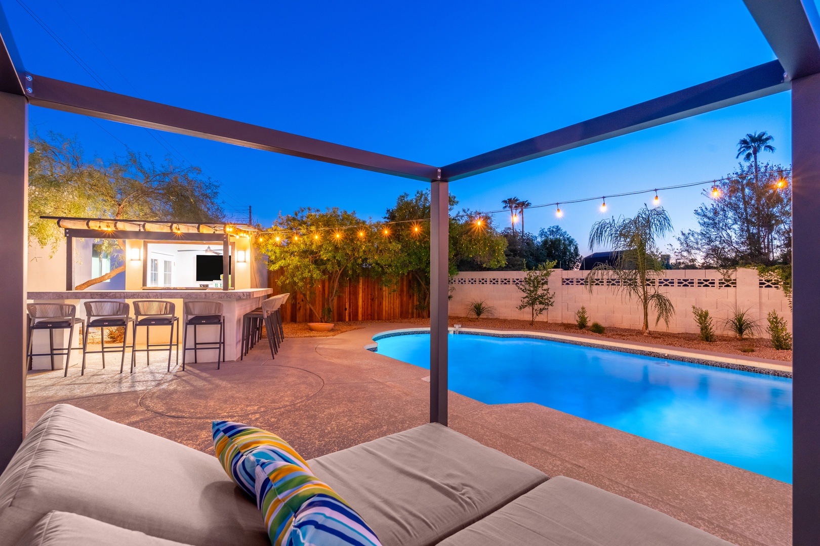 Unwind poolside under the stars as string lights glow and the water shimmers at twilight. Your private oasis awaits with bar seating and lounging spots perfect for evening relaxation.
