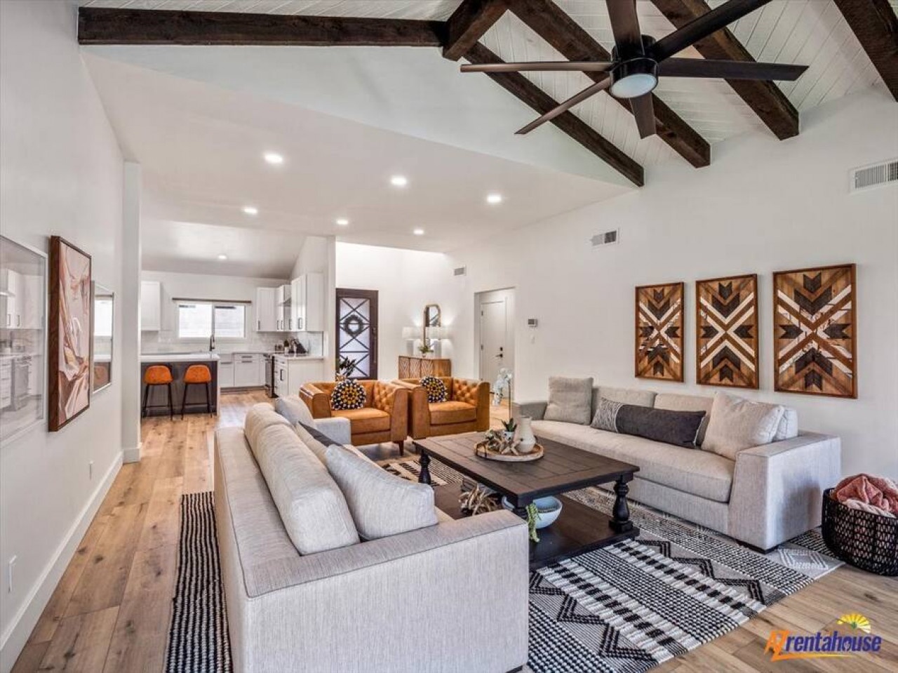 Sink into plush sectional seating beneath rustic exposed beams, where your open-concept retreat flows seamlessly into a bright modern kitchen.