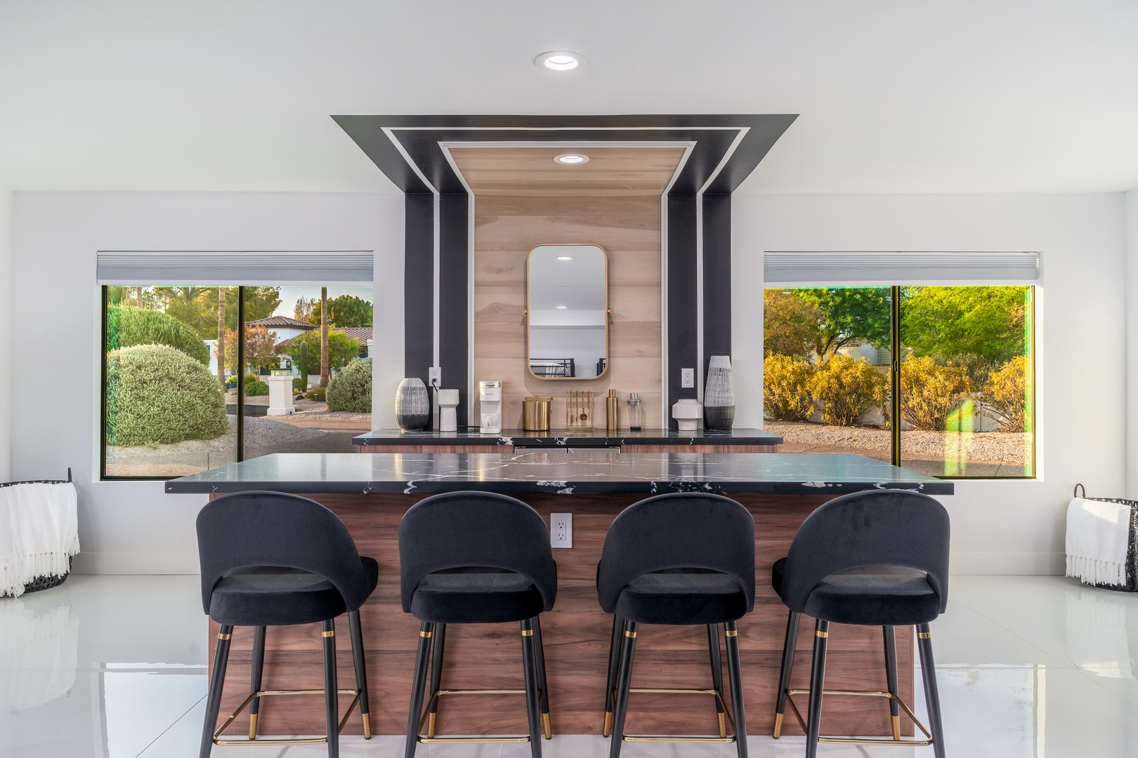 Elegant bar area featuring sleek black countertops, four plush stools, and stunning garden views through expansive windows—perfect for morning coffee or evening cocktails.