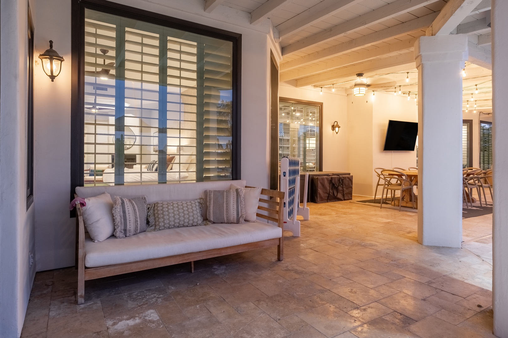 Unwind on this cozy covered patio, your perfect spot for morning coffee or evening relaxation. Inside, an open living and dining area awaits with warm wood beams and coastal charm.