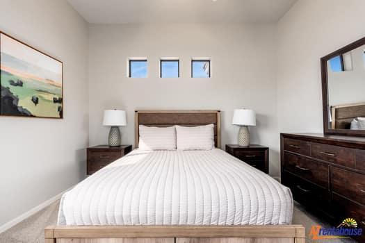 Relax in your serene bedroom with crisp linens, warm wood furniture, and natural light streaming through high windows.