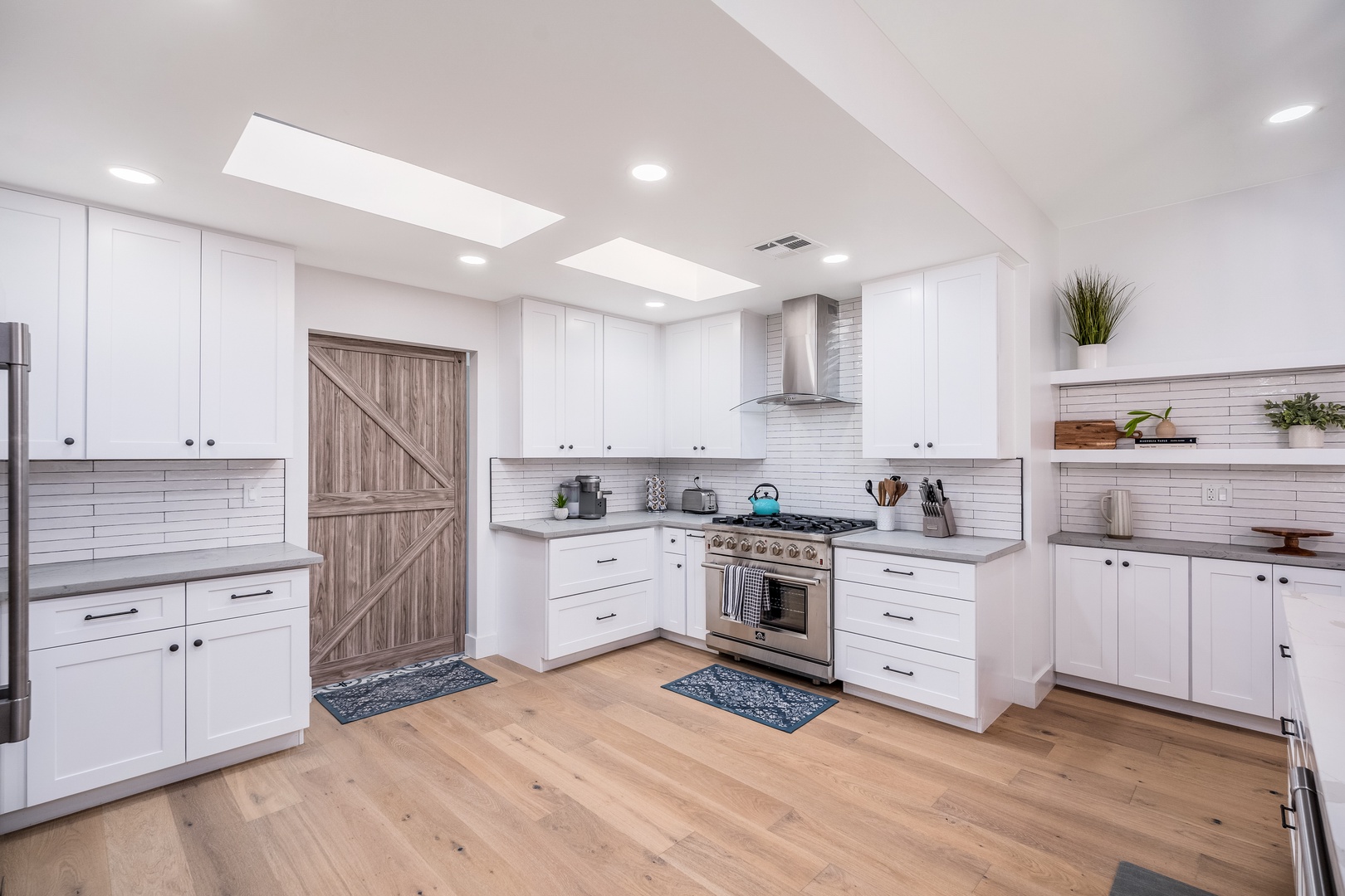 Step into your bright, airy kitchen where crisp white cabinetry and warm wood floors invite you to cook, gather, and make memories. Natural light pours through skylights as you prepare meals on professional-grade appliances.