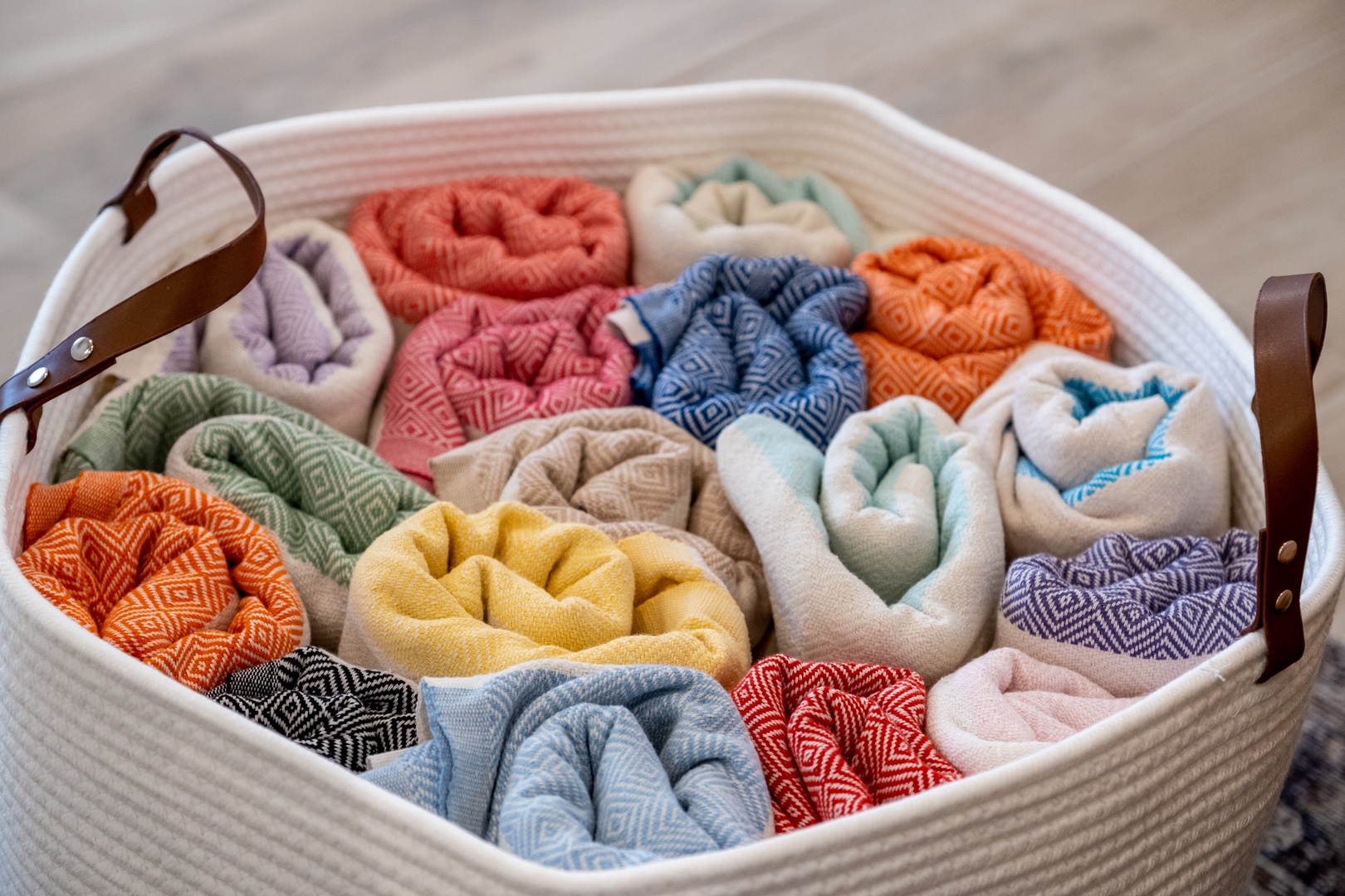 A colorful collection of plush towels awaits you, neatly rolled and organized for your comfort. Fresh linens in vibrant hues add a cheerful, welcoming touch to your stay.