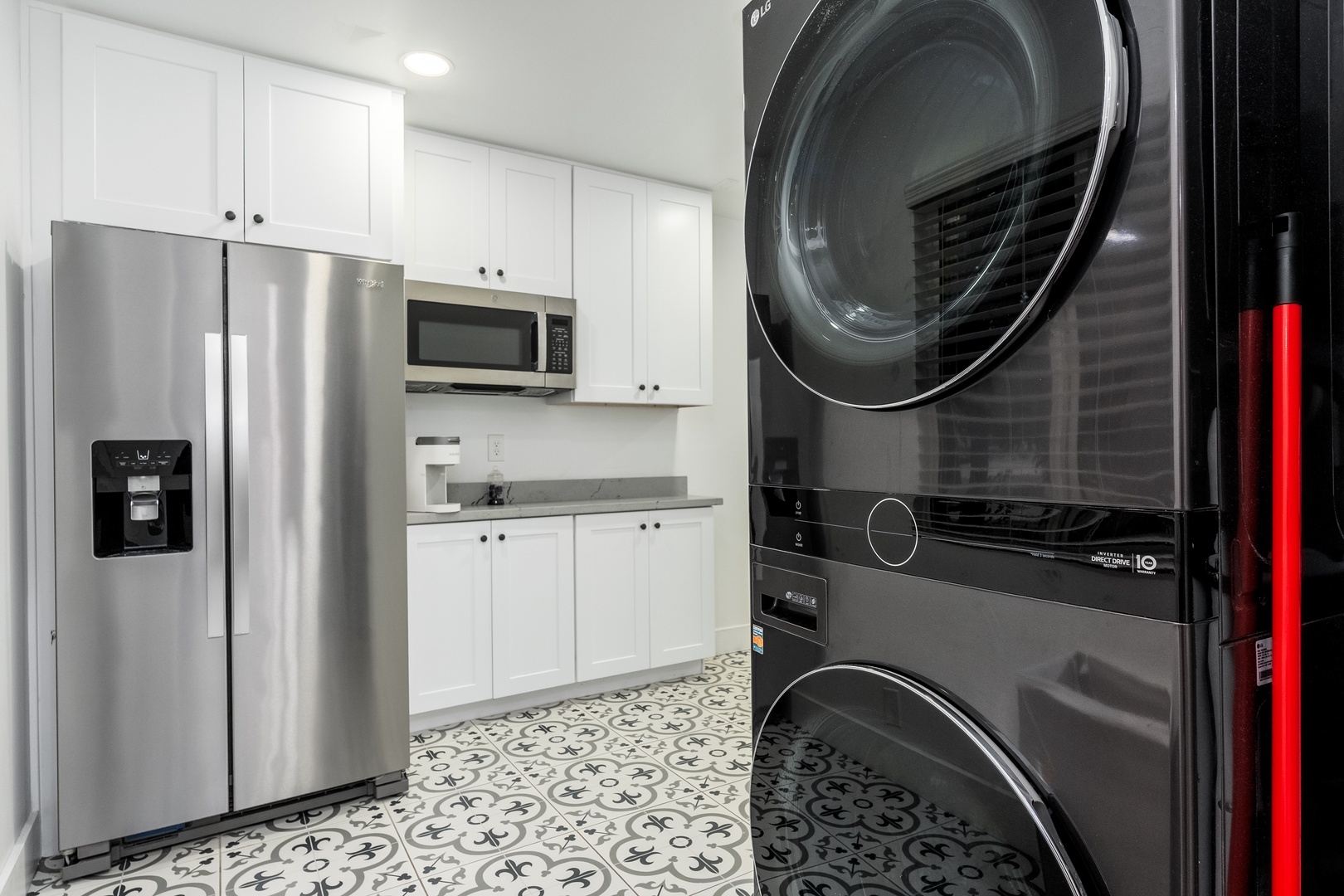 Your private laundry space features modern stacked washer and dryer units, a full-size refrigerator, and sleek white cabinetry—making longer stays effortless and comfortable.