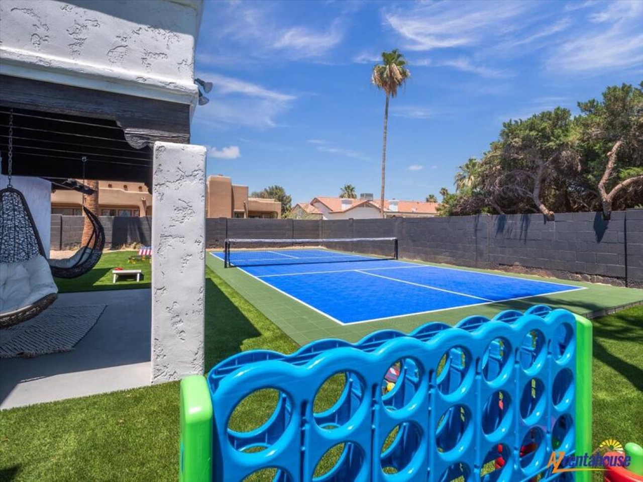 Your private backyard oasis features a full tennis court, cozy hanging chair, and Connect 4 fun—perfect for active days and relaxed evenings under palm trees.