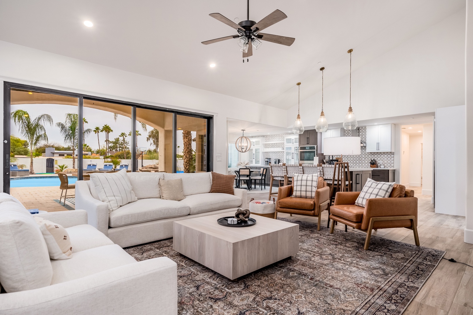 Unwind in your bright, open living space with stylish furnishings, where large sliding doors frame views of the sparkling pool and palm-studded backyard—your perfect retreat awaits.