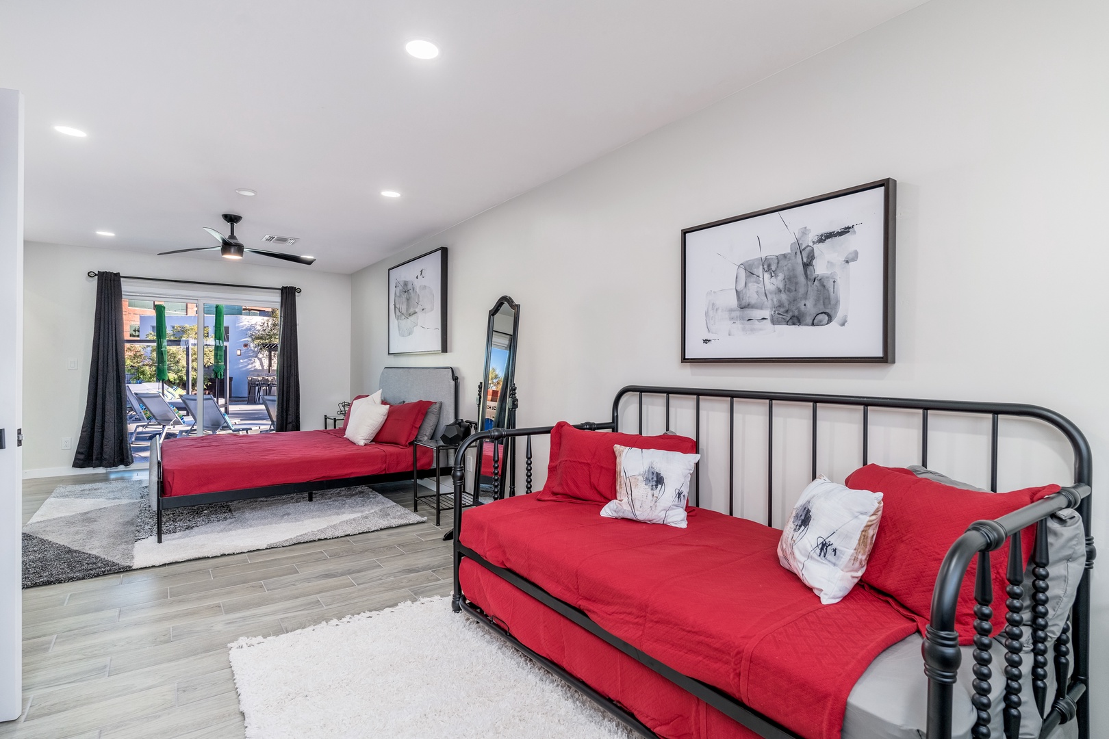 Unwind in your spacious bedroom where vibrant red bedding meets sleek modern design. Two comfortable beds invite restful nights, while the poolside view promises sun-soaked mornings just steps away from your door.