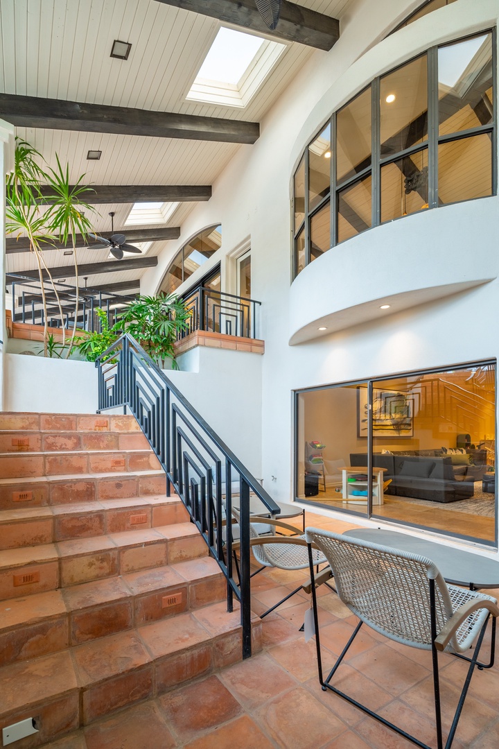 Step into your multi-level retreat where soaring skylights bathe exposed beams in natural light, and cozy seating nooks offer peaceful views of the open living spaces below.