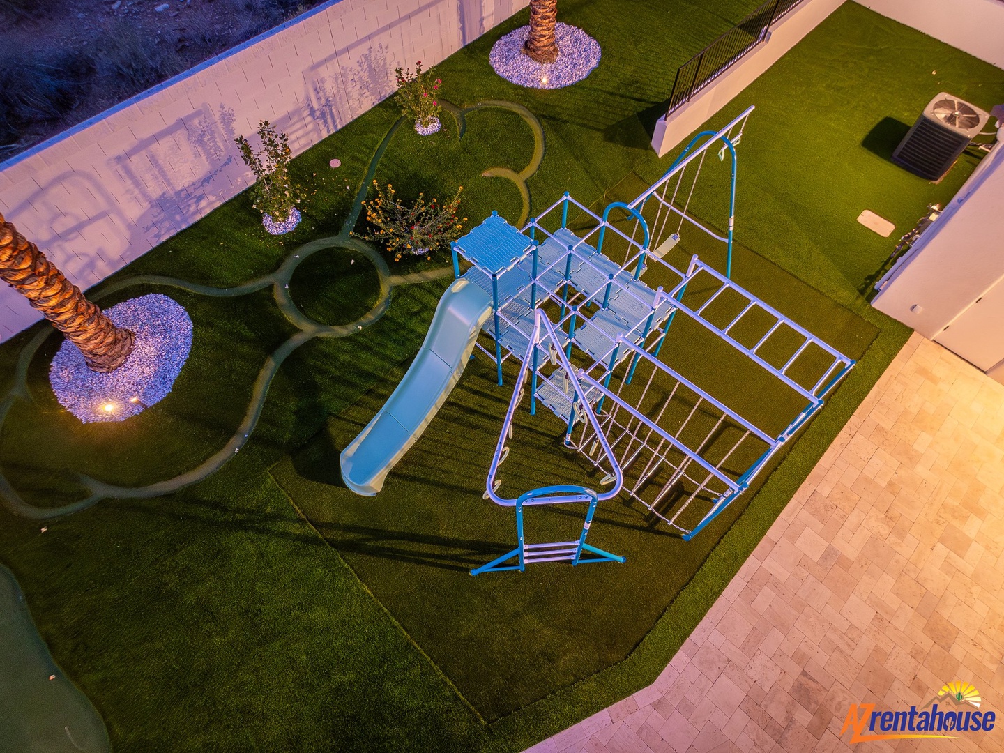 Aerial view reveals the property's playground area with slides and climbing equipment, surrounded by landscaped grounds and walking paths.