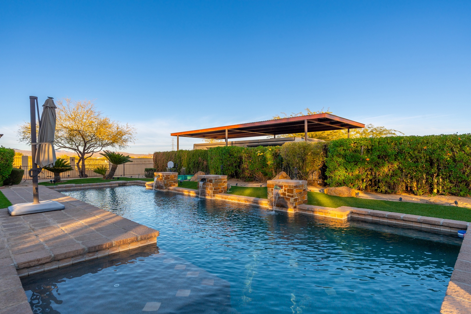 A stunning resort-style pool with stone waterfalls and sunbathing ledges awaits you, surrounded by desert landscaping and open skies—perfect for cooling off under the Arizona sun.
