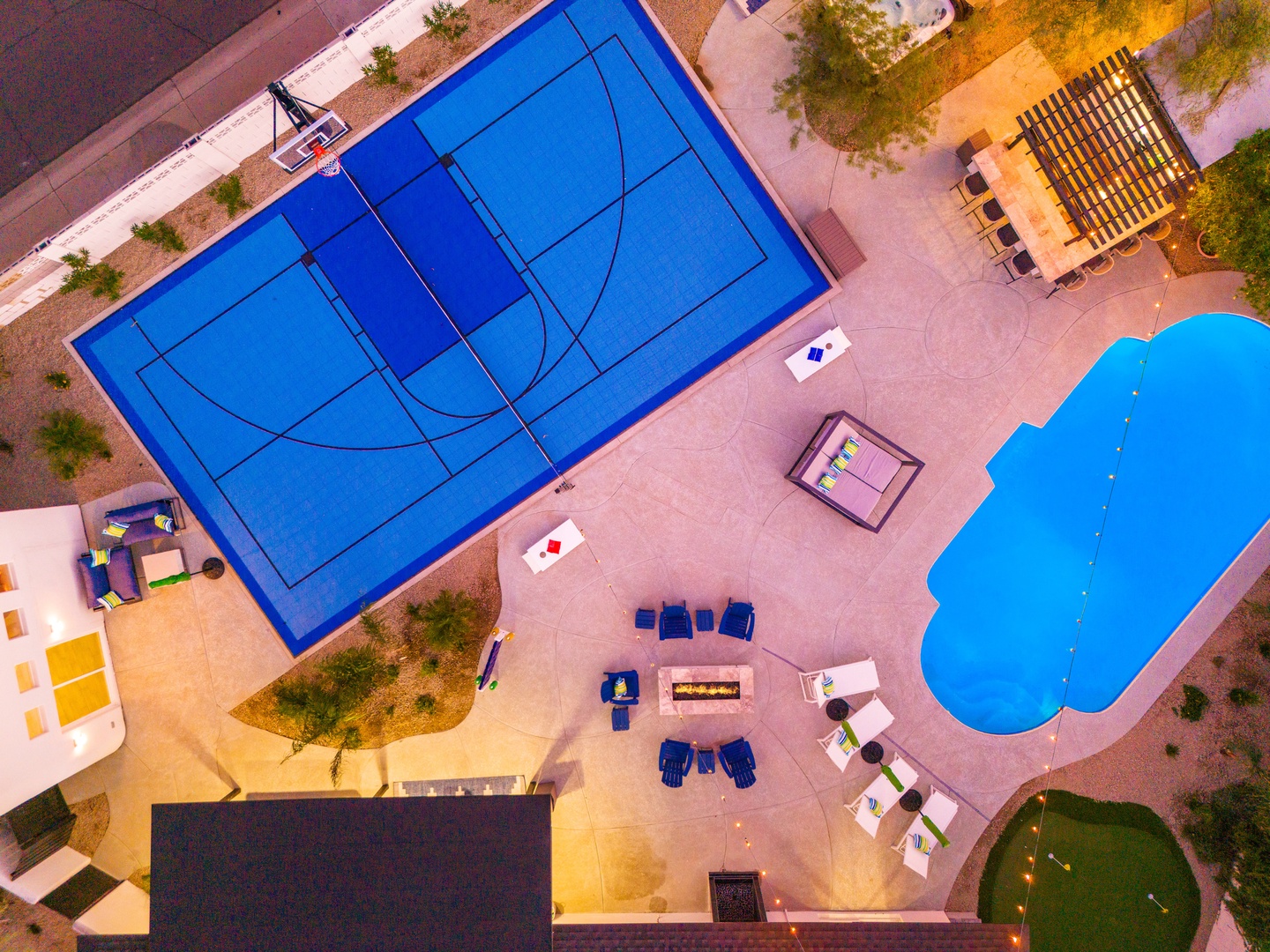 Aerial view of the property's expansive recreational area featuring a full basketball court, sparkling swimming pool, and outdoor entertainment spaces surrounded by desert landscaping.