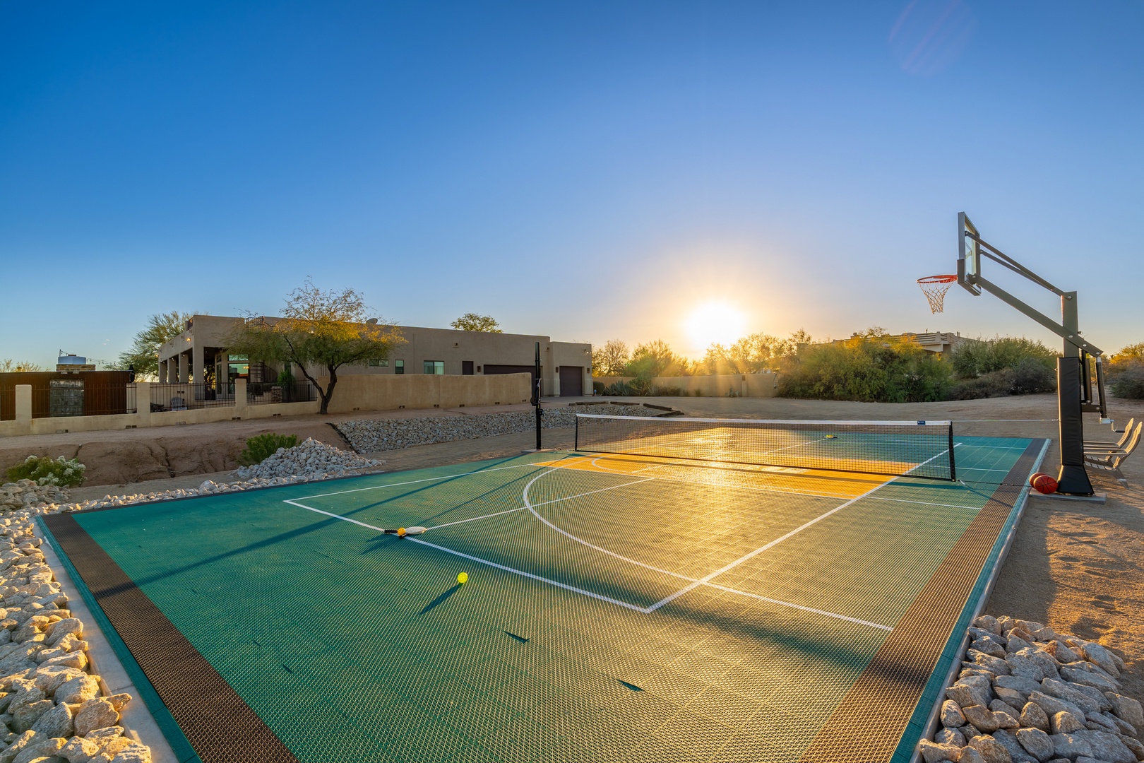 A multi-sport court set in desert landscaping offers a golden-hour backdrop for friendly basketball games and outdoor fun at this modern southwestern property.