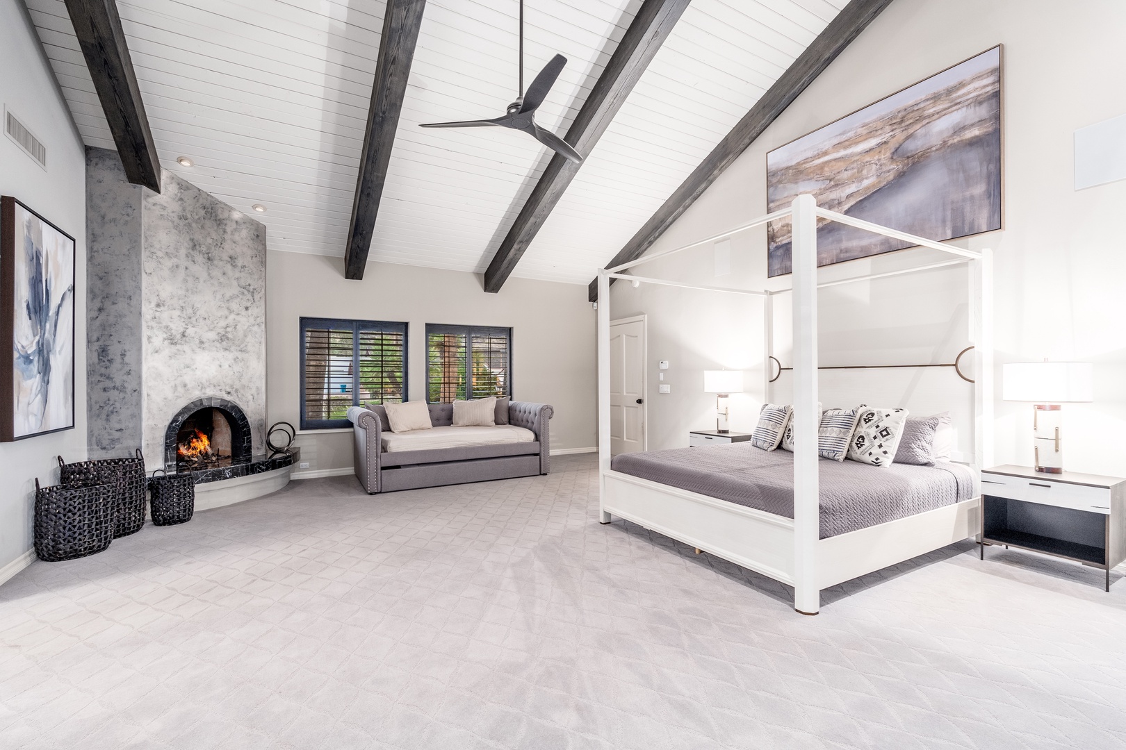 Unwind in your spacious bedroom suite, where vaulted ceilings with exposed beams frame a plush canopy bed. Sink into the cozy lounge by the crackling fireplace as natural light pours through shuttered windows.