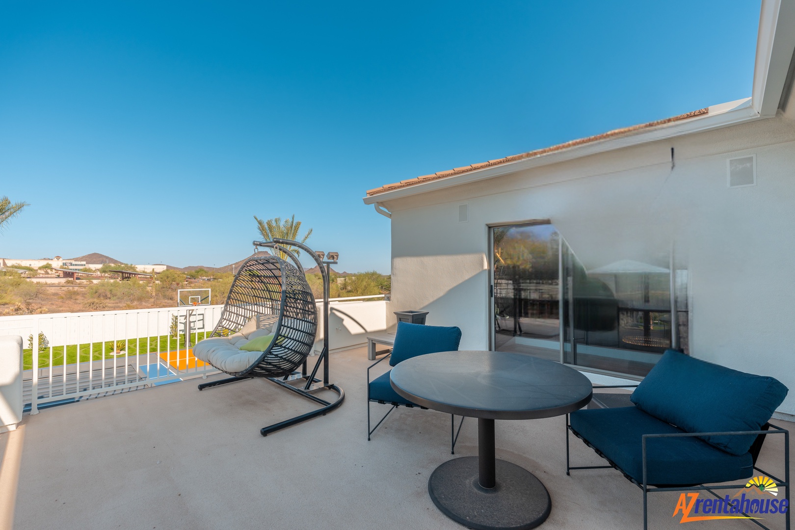 Your private terrace invites relaxation with a cozy hanging chair, stylish dining set, and stunning desert views.