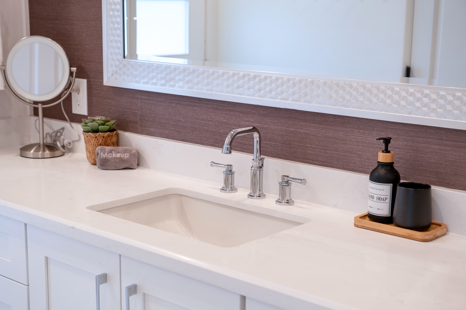 Your private bathroom features a sleek sink with elegant fixtures, a makeup mirror for getting ready, and thoughtful touches like hand soap and a succulent to make you feel right at home.