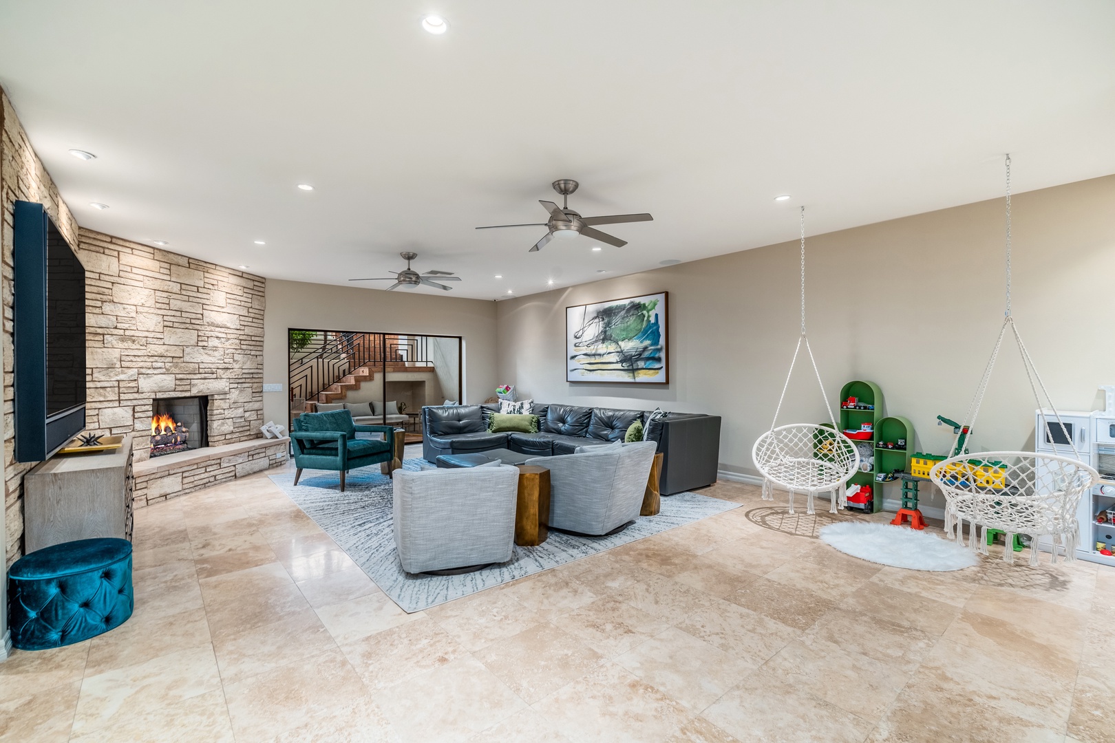 Spacious living room with cozy seating, stone fireplace, and dedicated play area—perfect for family gatherings and relaxing evenings together.