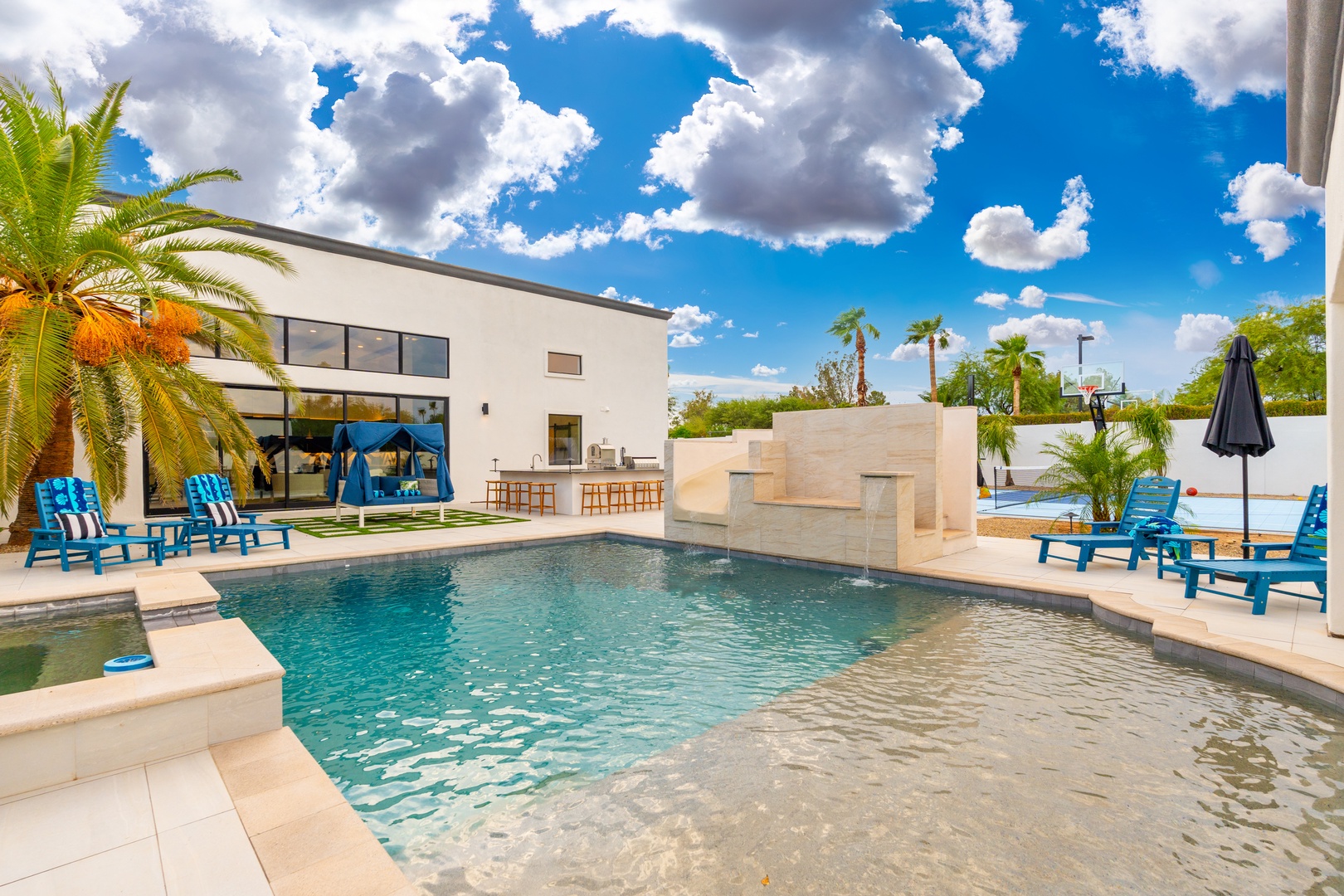 Contemporary oasis with sparkling pool, outdoor lounge, swim-up bar, and sun-soaked entertaining spaces under blue desert skies.