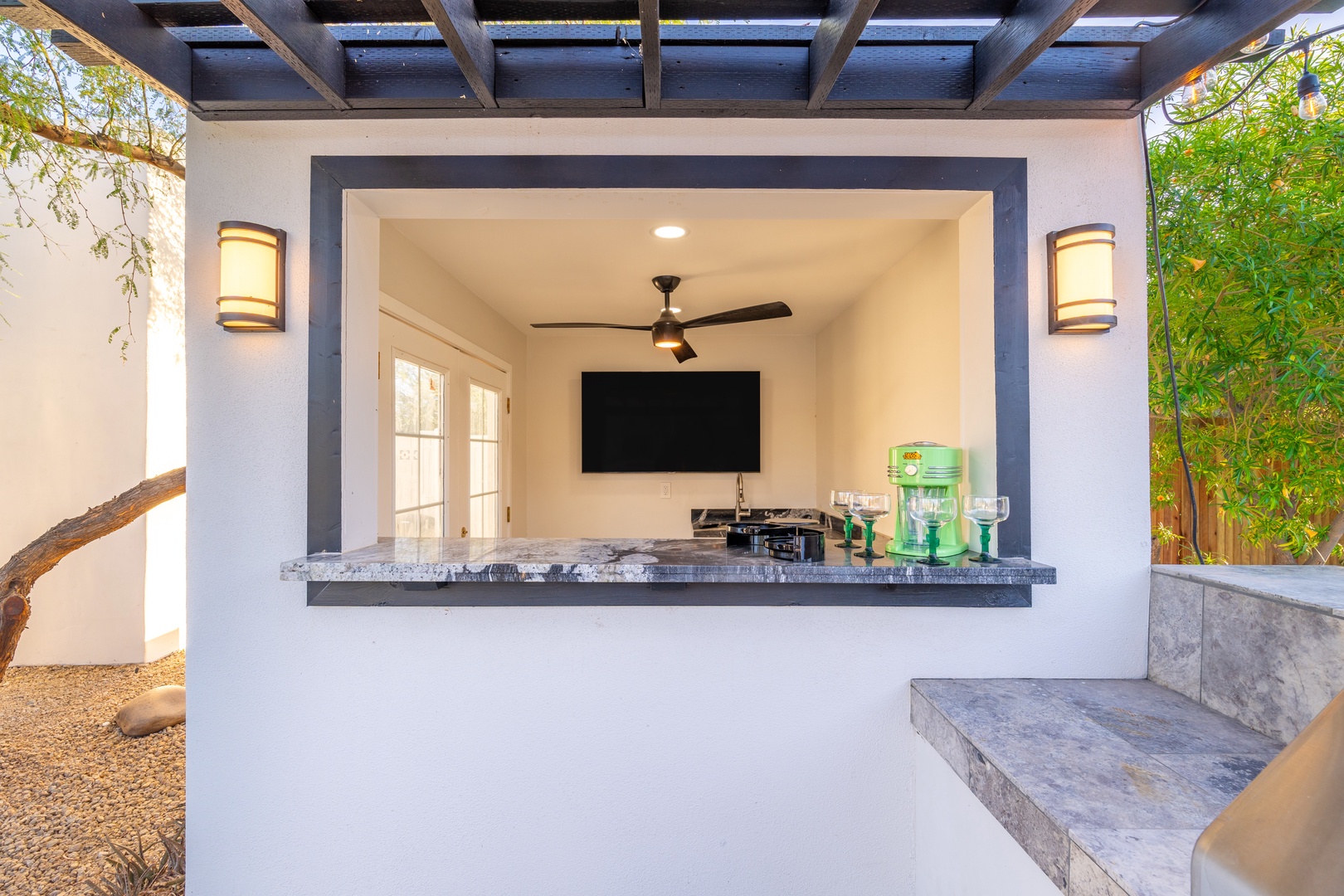 Your own outdoor entertainment hub awaits—watch the game, mix drinks at the bar, and soak up the desert ambiance under a pergola with lush greenery framing your view.