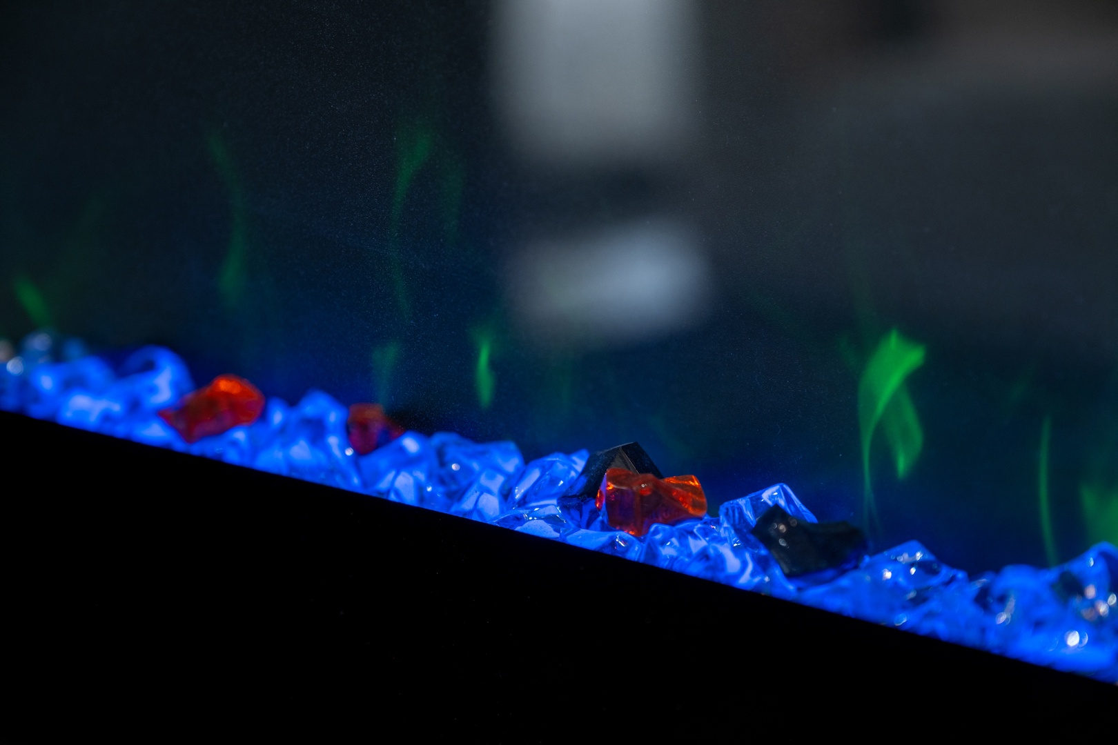 A mesmerizing fireplace feature with glowing blue glass embers and red accents creates a soothing ambiance, perfect for your cozy evenings in.