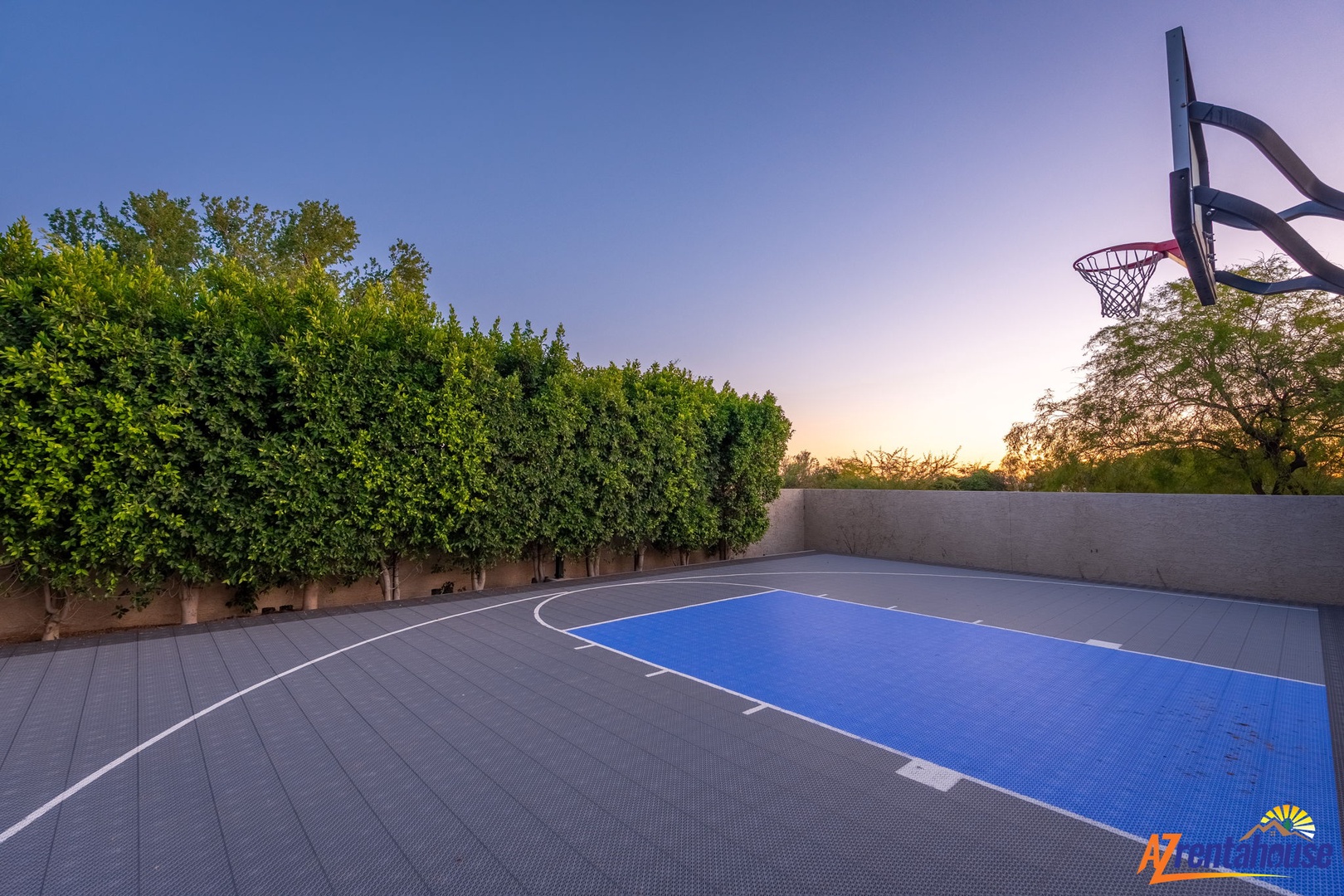 A private outdoor basketball court with professional surfacing, surrounded by lush landscaping and views of the sunset. Perfect for staying active during your stay.