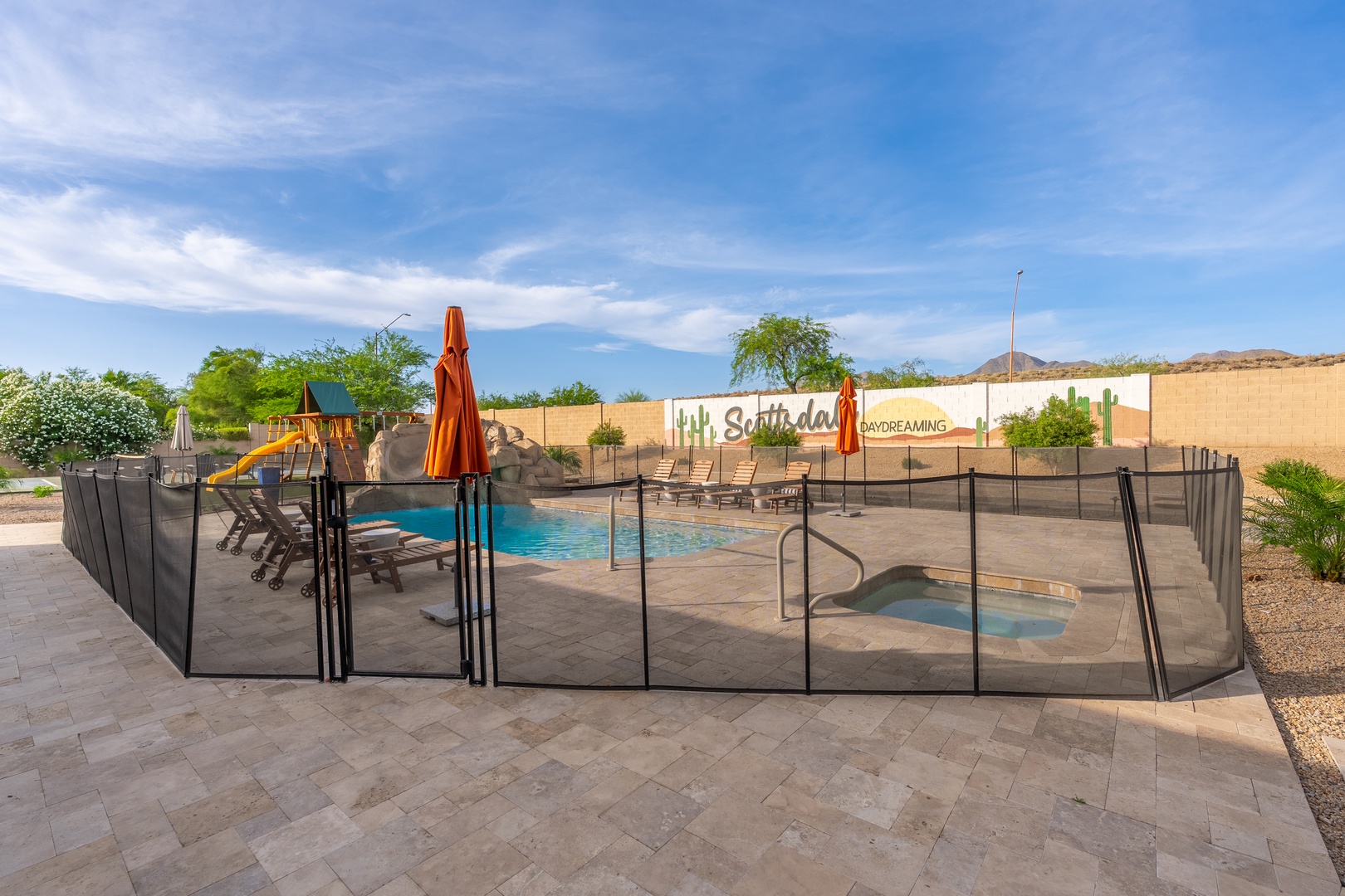 A spacious backyard oasis features a fenced pool for safe family fun, surrounded by desert mountain views and a nearby playground—perfect for sunny Arizona days.